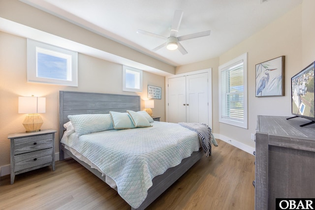 bedroom featuring a closet, baseboards, light wood finished floors, and multiple windows