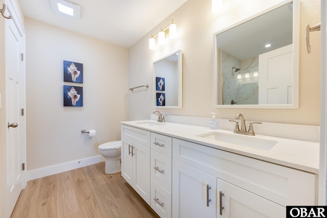 bathroom featuring double vanity, baseboards, a sink, and wood finished floors