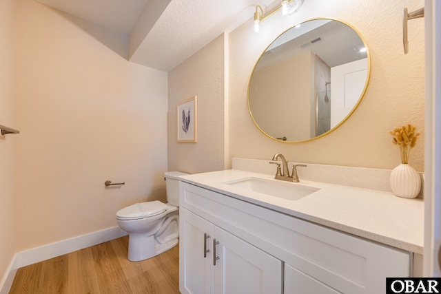 bathroom featuring baseboards, visible vents, toilet, wood finished floors, and vanity