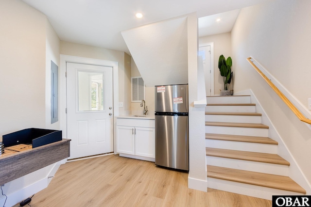 foyer entrance with light wood-type flooring, stairs, and recessed lighting