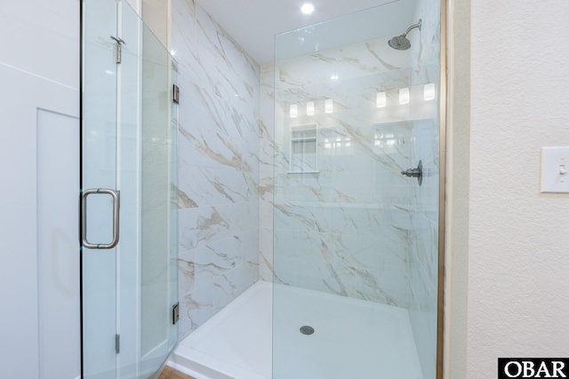 bathroom with a marble finish shower and a textured wall