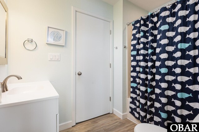 bathroom featuring toilet, curtained shower, wood finished floors, and vanity