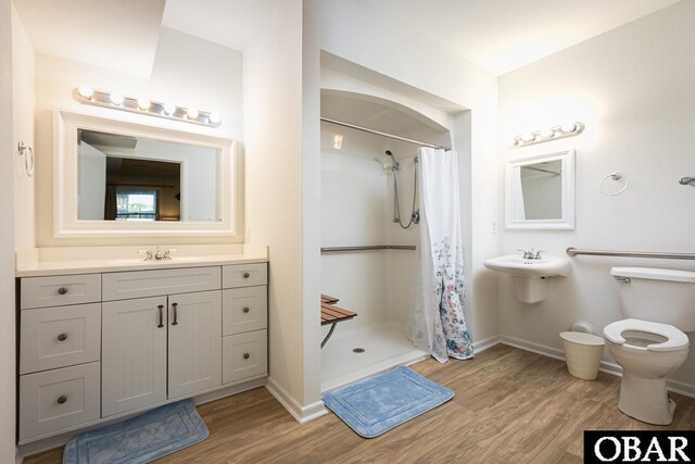 bathroom with a sink, a stall shower, baseboards, and wood finished floors