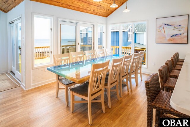 dining room featuring a water view, wooden ceiling, light wood-style flooring, and vaulted ceiling