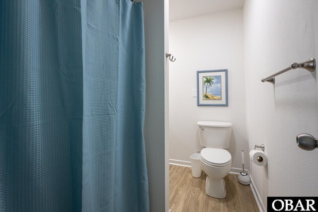 full bathroom with a shower with curtain, wood finished floors, toilet, and baseboards