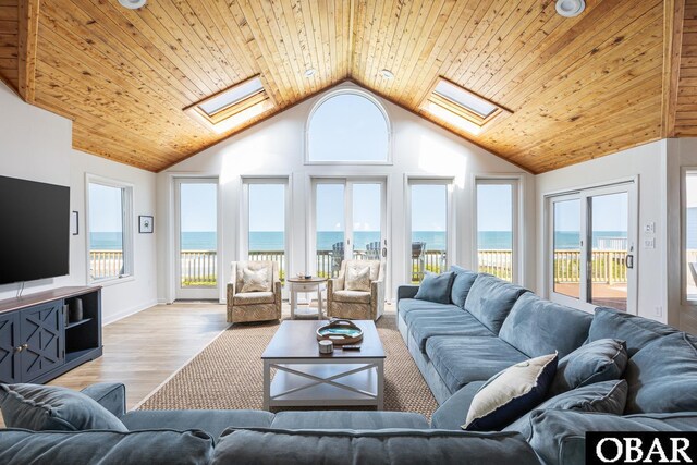 living area with light wood-style floors, a skylight, and a water view