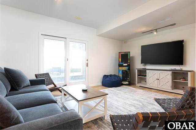 living room featuring track lighting, baseboards, and wood finished floors