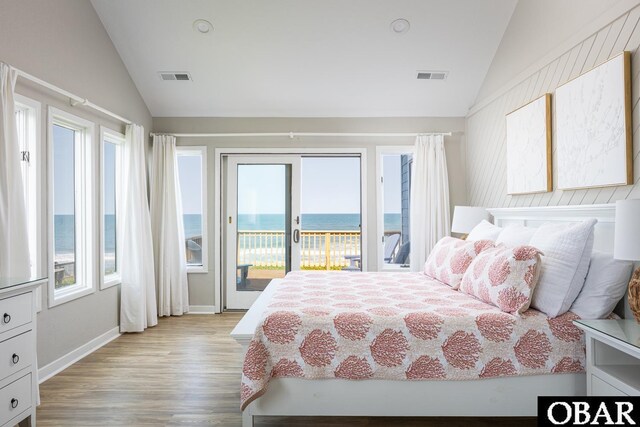 bedroom with lofted ceiling, a water view, and visible vents