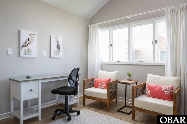 office featuring baseboards, vaulted ceiling, wood finished floors, and a textured wall