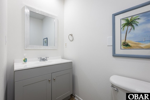 bathroom featuring baseboards, vanity, and toilet