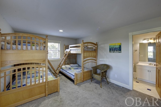 bedroom featuring ensuite bathroom, light tile patterned flooring, light carpet, visible vents, and baseboards