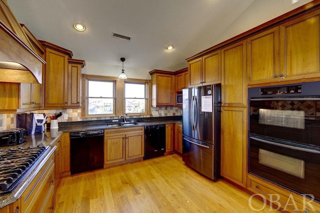 kitchen featuring dark countertops, visible vents, a sink, light wood-type flooring, and black appliances