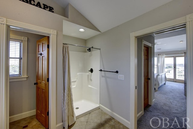 bathroom featuring a stall shower, vaulted ceiling, and baseboards