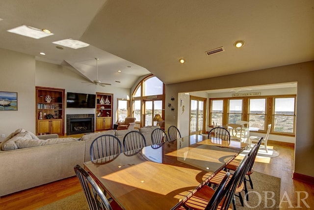 dining room featuring lofted ceiling, ceiling fan, a premium fireplace, light wood-style floors, and recessed lighting