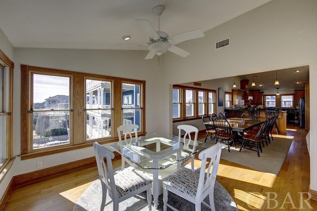 dining area featuring ceiling fan, high vaulted ceiling, visible vents, baseboards, and light wood-style floors