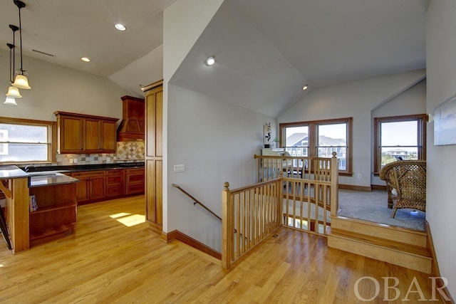 kitchen featuring dark countertops, lofted ceiling, a wealth of natural light, and decorative light fixtures