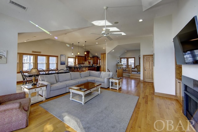 living room featuring light wood-style floors, a healthy amount of sunlight, visible vents, and a fireplace