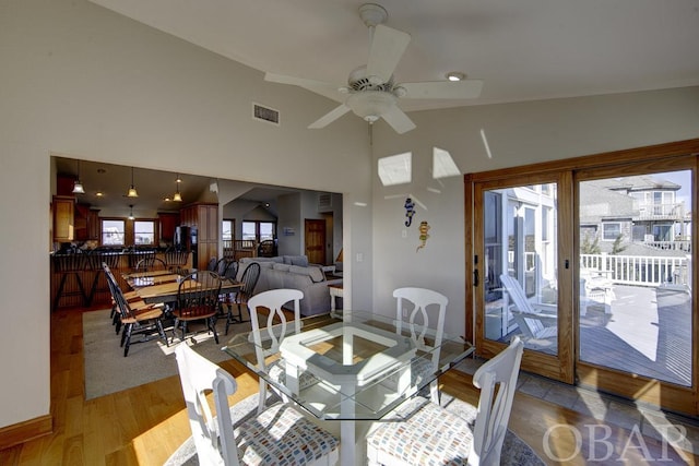 dining room featuring light wood-style floors, ceiling fan, a high ceiling, and visible vents