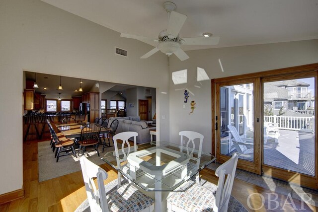 dining room featuring light wood-style floors, ceiling fan, a high ceiling, and visible vents