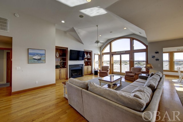 living room featuring high vaulted ceiling, visible vents, and light wood finished floors