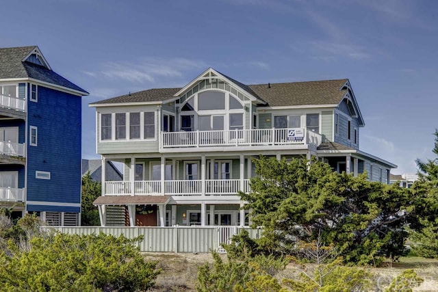 rear view of house with fence and a balcony