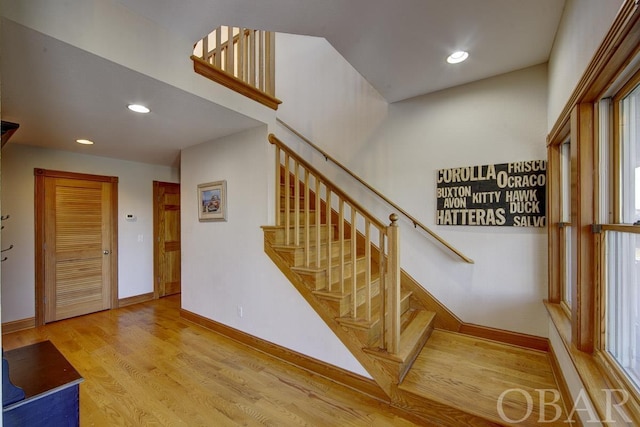 stairway featuring baseboards, wood finished floors, and recessed lighting