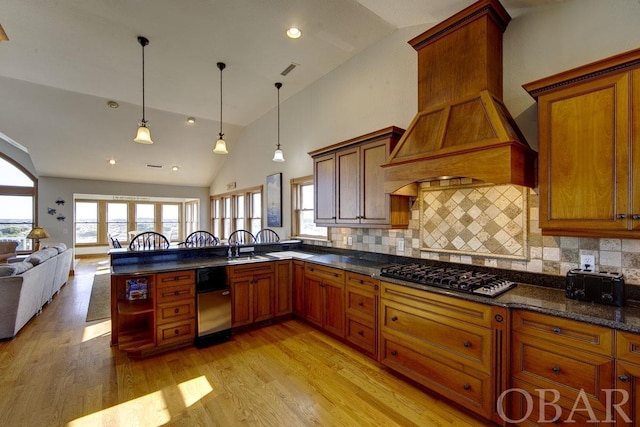 kitchen featuring decorative light fixtures, stainless steel gas stovetop, light wood-style flooring, open floor plan, and premium range hood