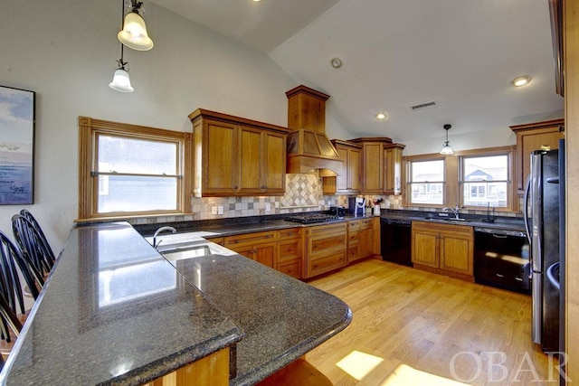 kitchen featuring visible vents, lofted ceiling, custom range hood, appliances with stainless steel finishes, and pendant lighting