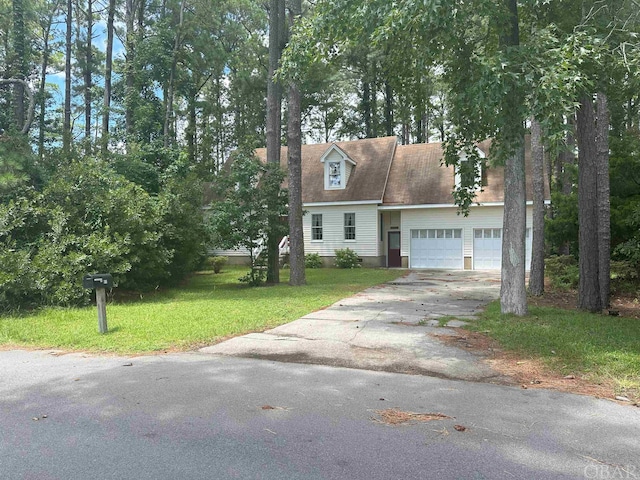 new england style home with aphalt driveway, a front yard, and an attached garage