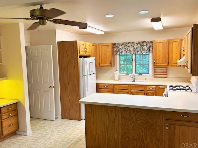 kitchen featuring white appliances, range hood, light countertops, and a sink