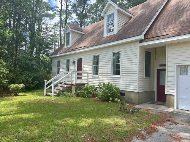 new england style home featuring a garage, a front yard, crawl space, and roof with shingles