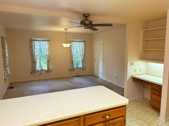 kitchen featuring visible vents, built in study area, brown cabinets, light countertops, and pendant lighting