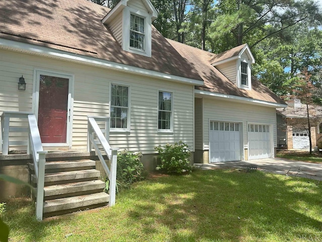 new england style home featuring an attached garage, concrete driveway, roof with shingles, and a front yard