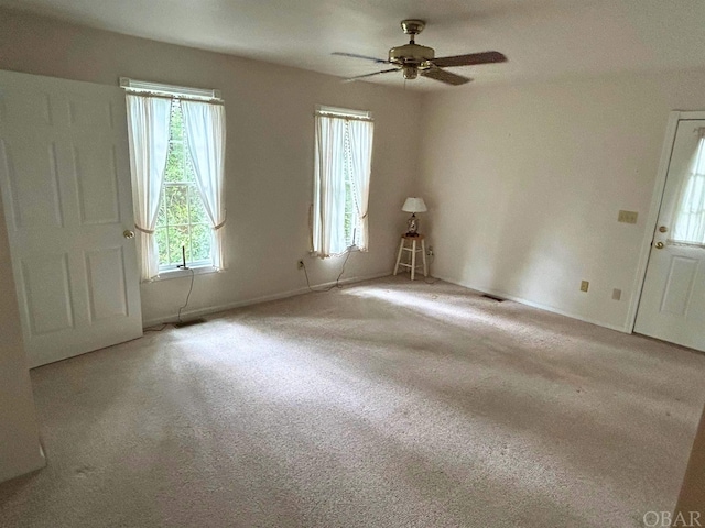 unfurnished room with visible vents, baseboards, a ceiling fan, and light colored carpet