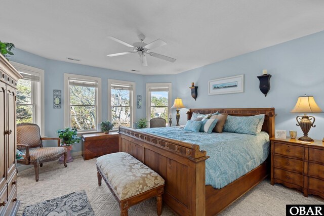 bedroom featuring light carpet, multiple windows, visible vents, and a ceiling fan