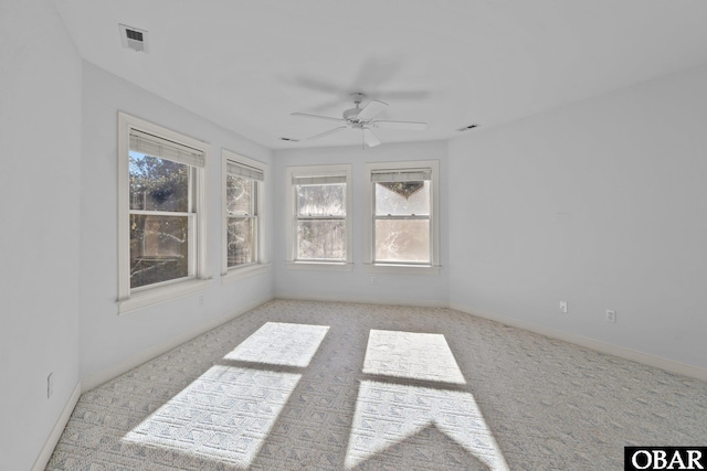 spare room featuring light colored carpet, visible vents, and plenty of natural light