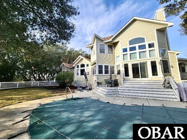 rear view of house featuring a fenced in pool, fence, a chimney, and a patio