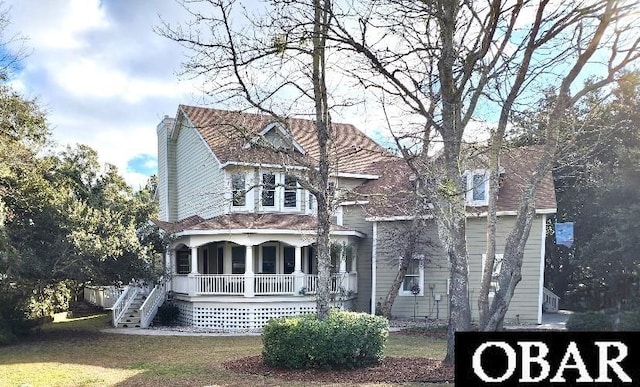 view of front of house with a porch, a front yard, a chimney, and stairs