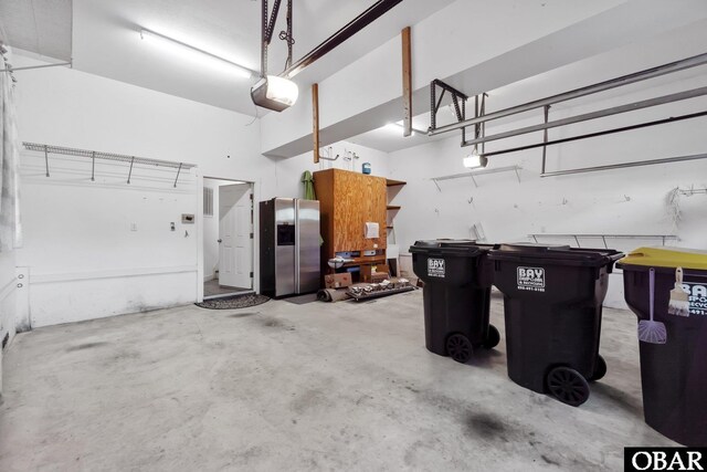 garage with a garage door opener and stainless steel fridge