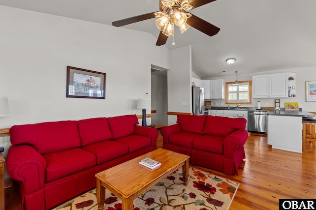 living area with light wood-style floors, a ceiling fan, and vaulted ceiling