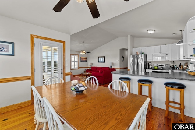 dining area featuring light wood-type flooring, ceiling fan, and vaulted ceiling