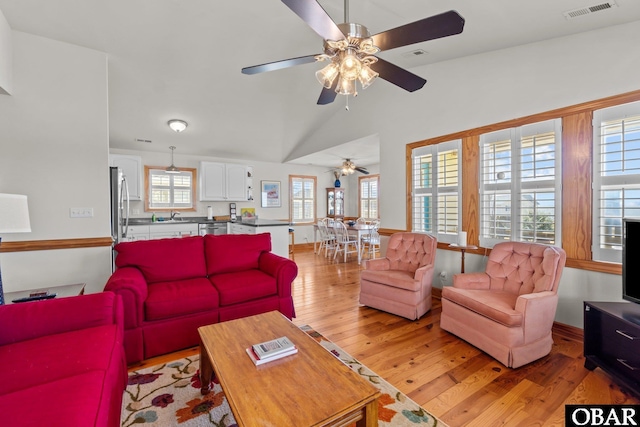 living room with vaulted ceiling, light wood-style floors, visible vents, and ceiling fan