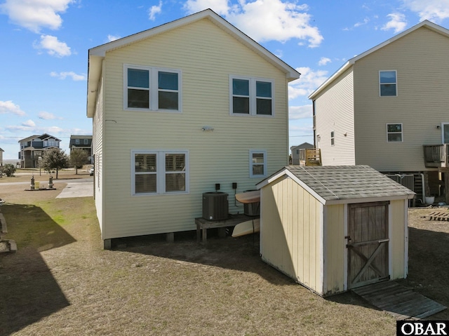 back of house with a storage shed, an outbuilding, and central AC