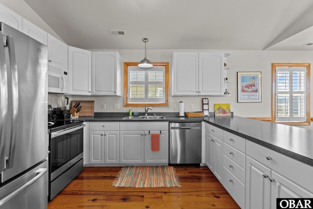 kitchen featuring visible vents, a sink, appliances with stainless steel finishes, white cabinetry, and dark countertops