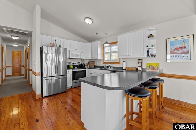 kitchen with dark countertops, visible vents, appliances with stainless steel finishes, a peninsula, and a sink