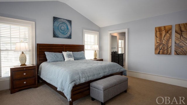 bedroom with light carpet, vaulted ceiling, and ensuite bathroom