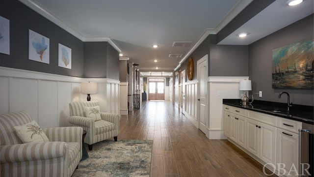 interior space featuring dark countertops, ornamental molding, open floor plan, white cabinetry, and a sink