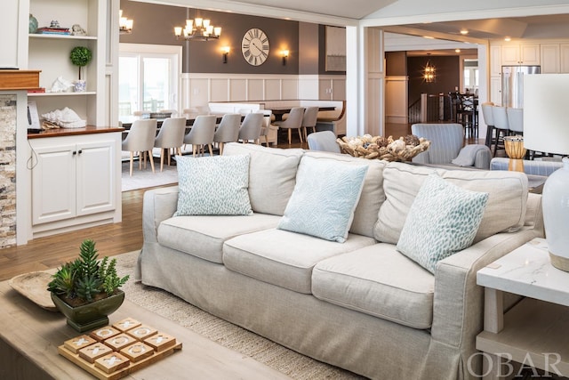 living area featuring a chandelier, wainscoting, light wood-style flooring, and a decorative wall