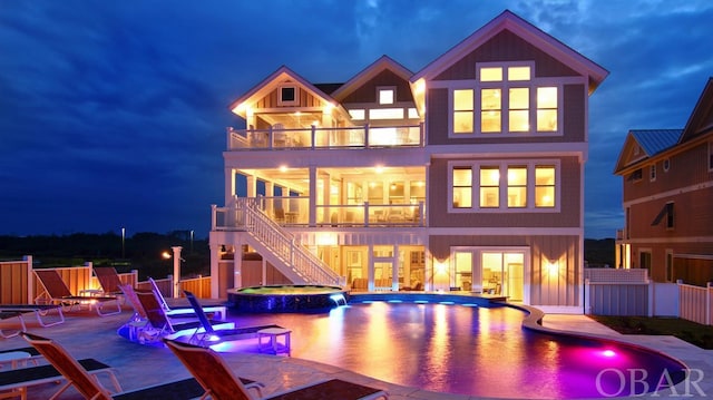 rear view of house with a patio, a balcony, stairs, fence, and a pool with connected hot tub