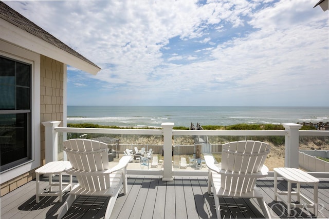 wooden deck featuring a beach view and a water view